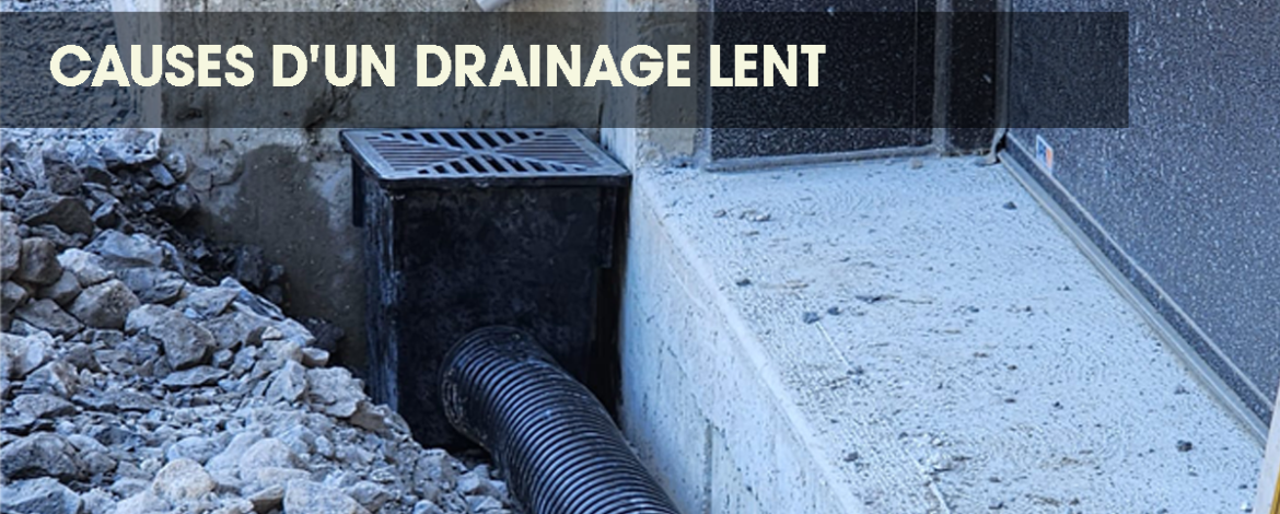 Black drainage pipe leading to an underground grate in a garden with sparse grass