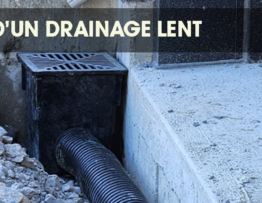 Black drainage pipe leading to an underground grate in a garden with sparse grass